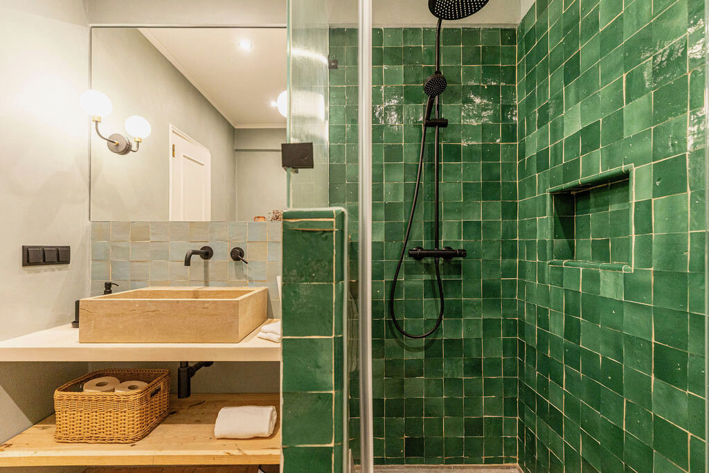 Emerald zellige bathroom with a walk-in glass shower and stone basin on wood