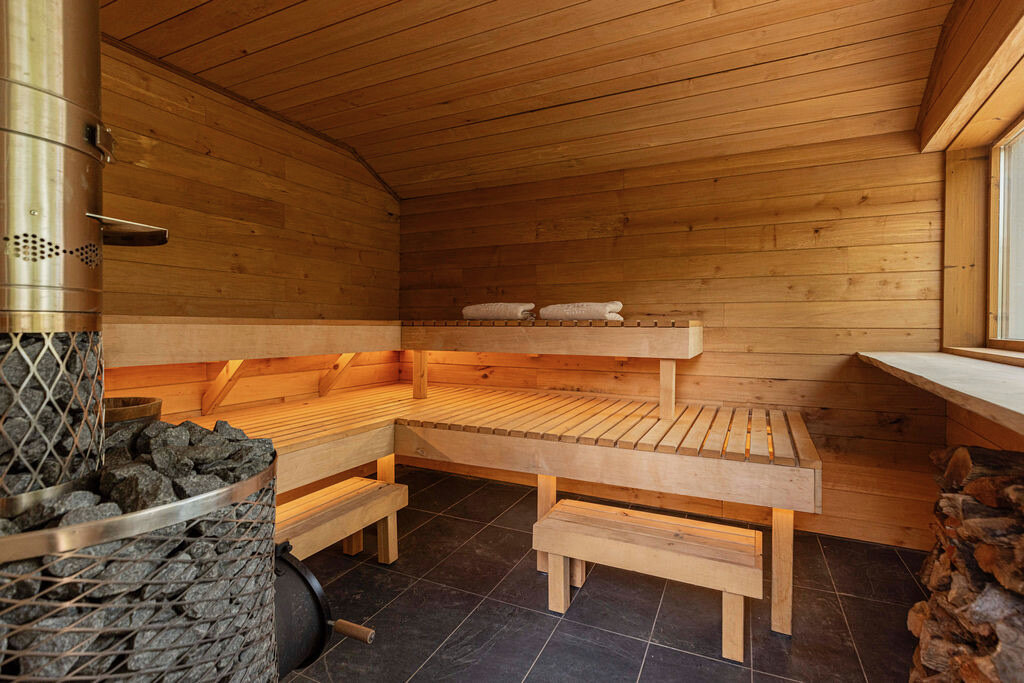 Finnish sauna interior — pale wood benches and a stone-filled heater