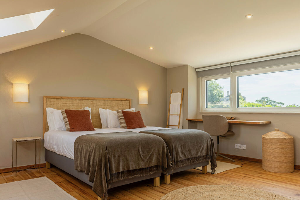 Bedroom three — twin beds under the sloped ceiling, desk and window at the right