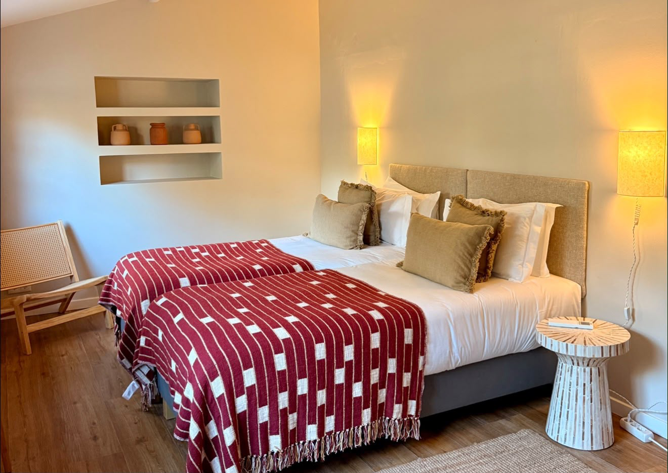 Twin beds with red-and-white woven throws, wall niches holding terracotta pots and warm sconces