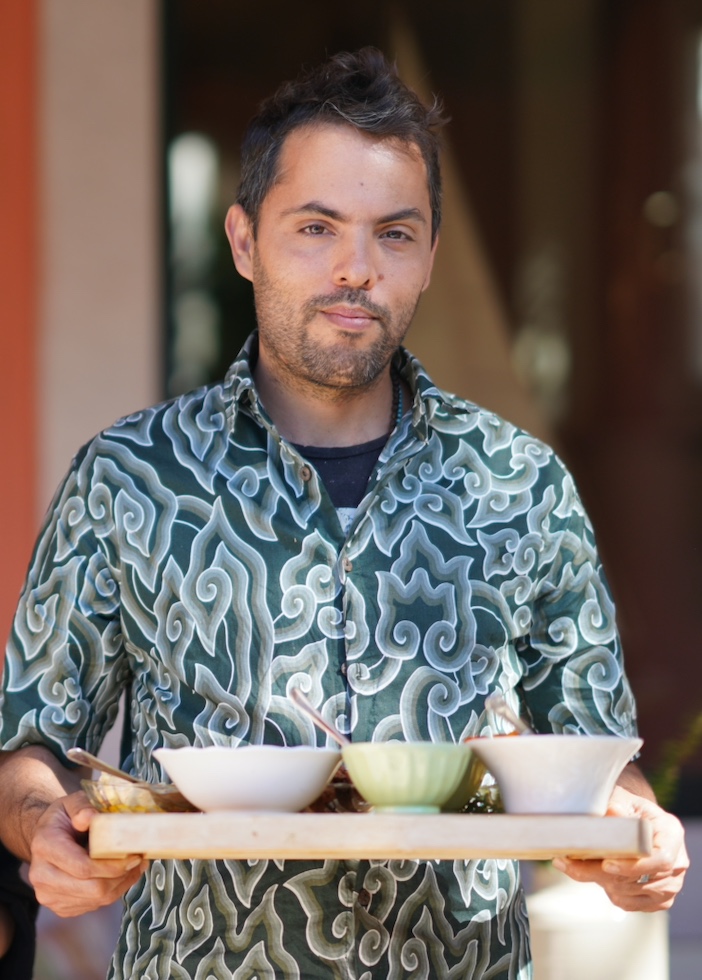 Chef Jivan carrying a tray of small bowls onto the terrace at Casa Pavão