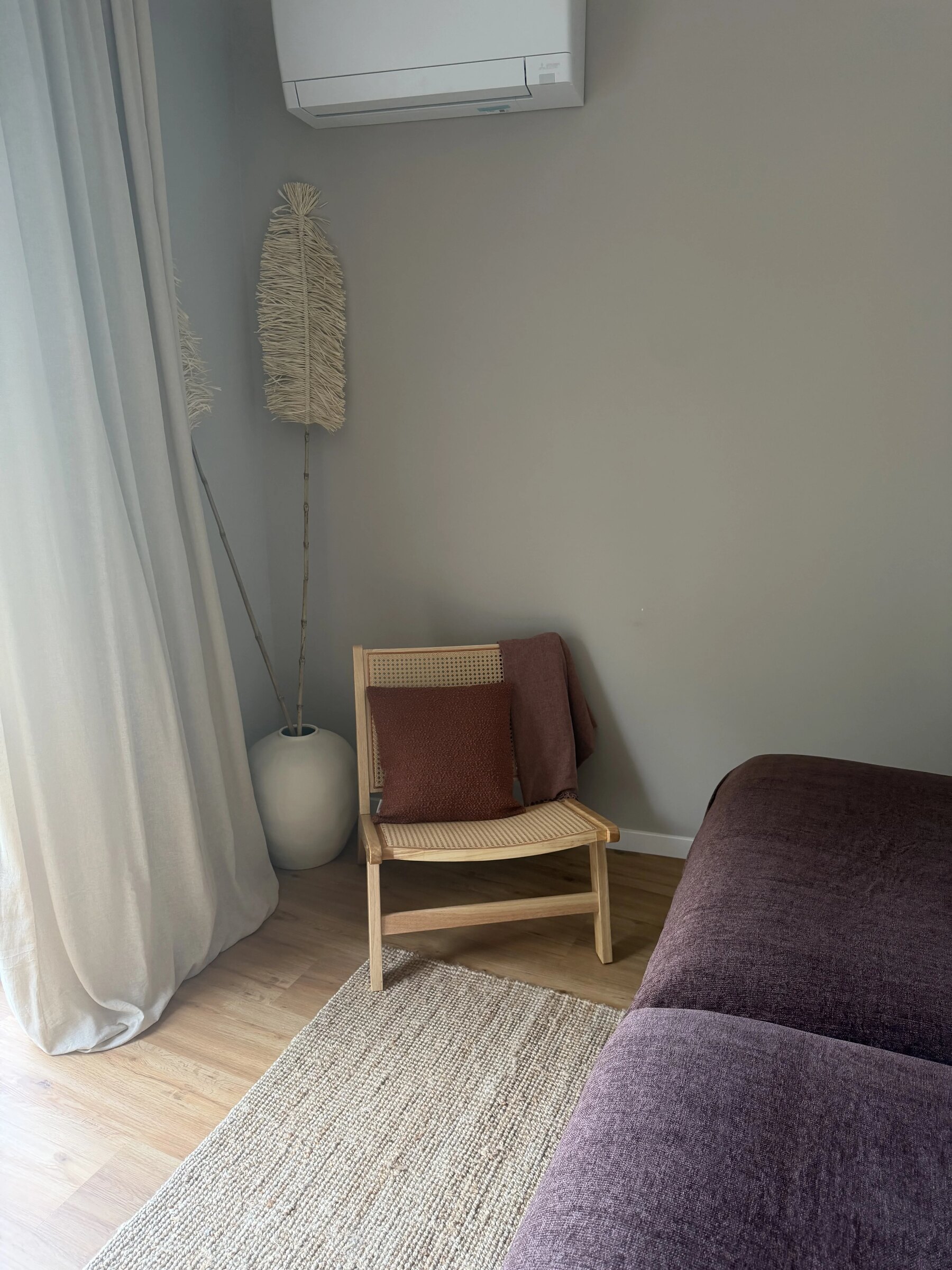 A cane lounge chair in the corner with a soft throw