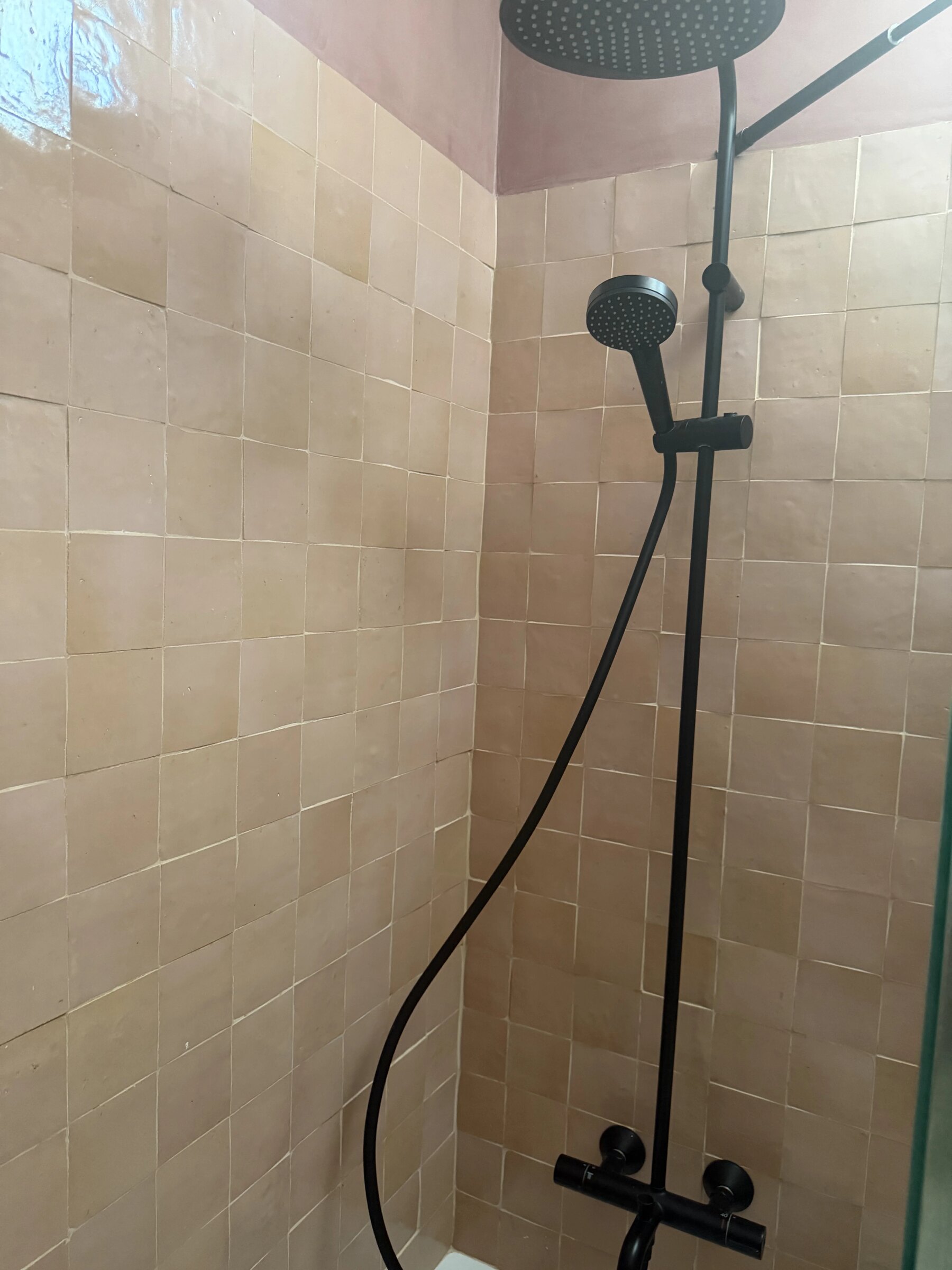 Shower in beige zellige with a black rain shower head